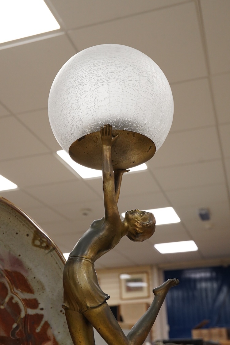 An Art Deco spelter ‘Dancing Girl’ table lamp with a frosted glass globe shade, 57cm high